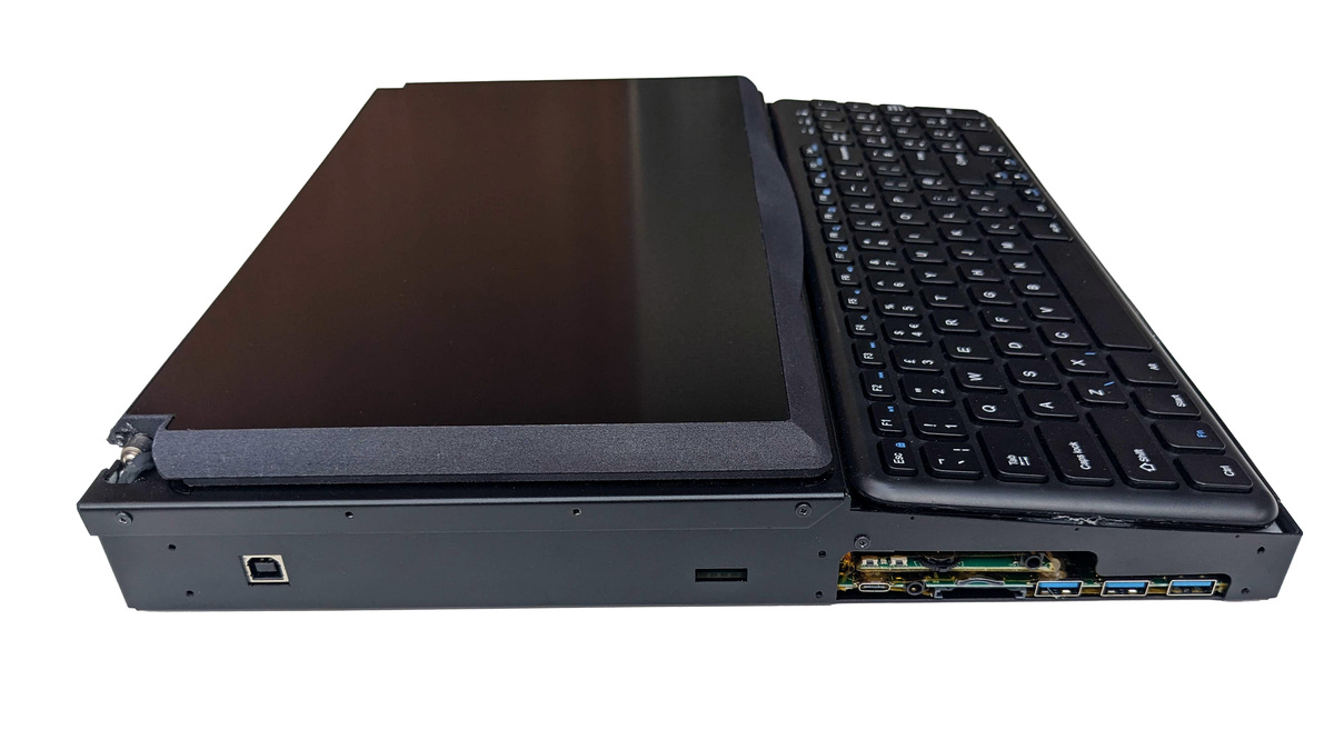Side on photo of the left side Canute Scientific when closed. The lid is closed over the Braille display. A range of ports are accessible, including USB-B, USB-C, 3.5mm audio jack, SD card and three USB-A. The chassis is a three part folded black aluminium with accessible screws for customer repair, maintenance or modification.